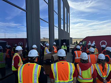 The President’s Executive Leadership Institute cohort stands in safety gear and hard hats during a tour of the Discovery District.