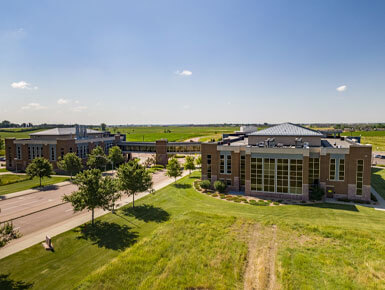 An exterior picture of the USD – Sioux Falls campus, displaying two buildings connected by a skywalk.
