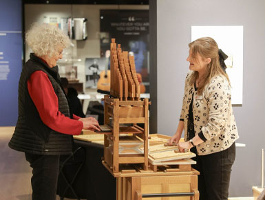 Anna Van Kley stands in front of a visitor at the National Music Museum, showing her an instrument.