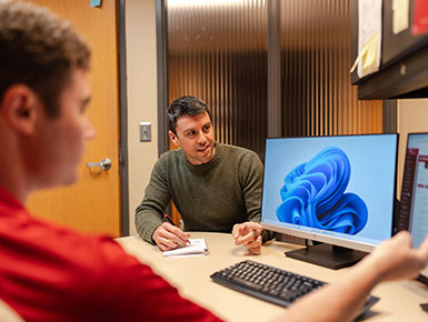 Buck Welch works at a computer with a community member. 