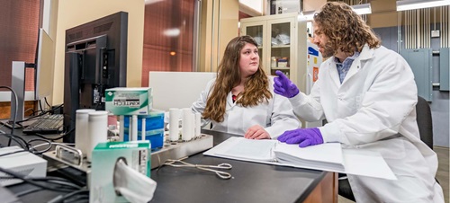 Male and Female in White Lab Coats Discussing Research Results